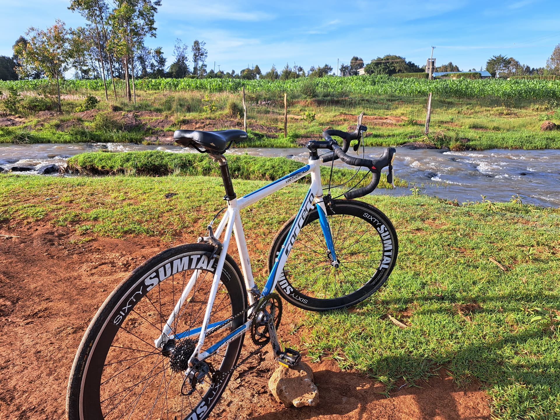 Brian's first bike, a white and blue Carrera, standing by a river in Eldoret