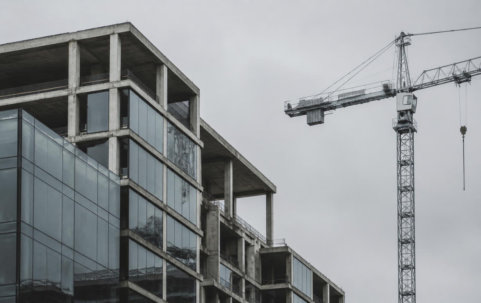 Concrete and glass building under construction beside a tower crane